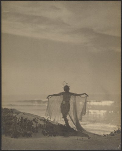 [Bagsidebillede af en danser iført et gennemsigtigt kostume på stranden]. af Arthur F. Kales