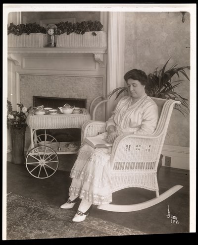 Mrs. Howard sad med en bog i en gyngestol i sit hjem på 200, 5th Avenue, New York, 1915-6 (sølv gelatinetryk) af Byron Company