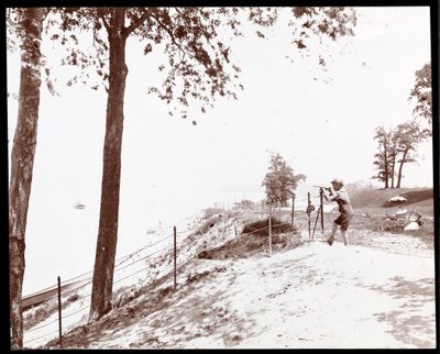 Udsigt af en dreng med et kikkertglas, der kigger mod Hudson River fra Riverside Park, New York (sølv gelatinetryk) af Byron Company