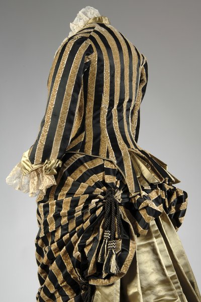 Aftenkjole, ca. 1884 (skrå bagside delvis udsigt). Silke satin og skåret fløjl, blonder, silketråd kvaster og frynser. Charles Frederick Worth, Frankrig. af Charles Frederick Worth