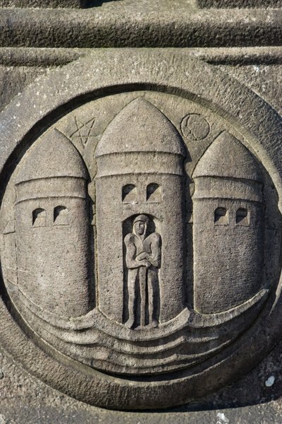 Tre tårne-symbol hugget i en stensøjle på Rådhuspladsen af Danish School