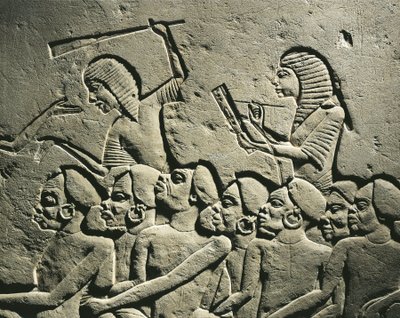 En gruppe negroide fanger omgivet af vagter bevæbnet med køller, mens en skriver udfærdiger en rapport. Relief fra Horemhebs grav i Saqqara, detalje af Egyptian 18th Dynasty