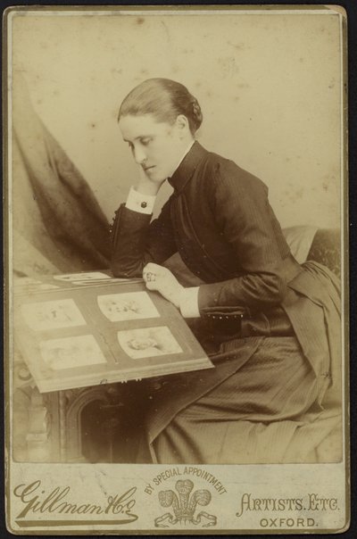 Figur af en kvinde, der sidder og inspicerer et fotoalbum af English Photographer