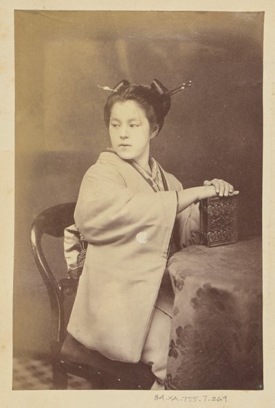 [Siddende japansk kvinde med et cartes-de-visite-album ved et bord]. af Felice Beato