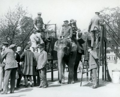 Besøgende, der står i kø til en elefanttur, mens andre går om bord med hjælp fra fem vogtere, London Zoo, 1927 af Frederick William Bond