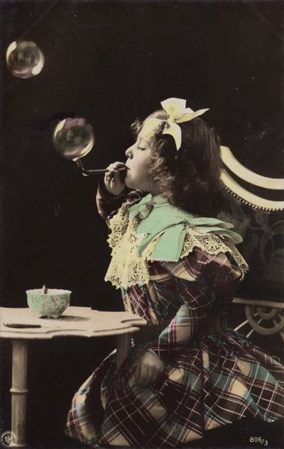 En lille pige blæser bobler fra et rør (tonet billede) af French Photographer