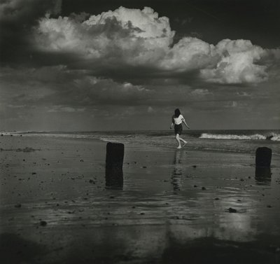 Et barn leger med bølgerne på stranden. af Godfrey Macdominic