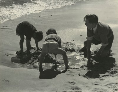 Tre børn leger med sand på stranden. af Godfrey Macdominic