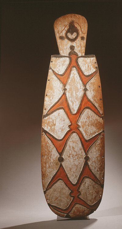 Ovalt Asmat-skjold, udskåret i relief med stiliserede figurer, en maske øverst (træ) af Guinean New