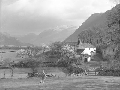 En mand går mod en vej og Gillerthwaite House, med søen og fjeldet i baggrunden. af Joseph Hardman
