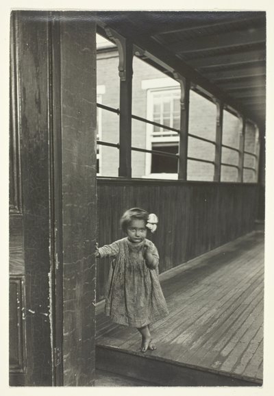 Lille pige står ved indgangen til et galleri af Lewis Wickes Hine