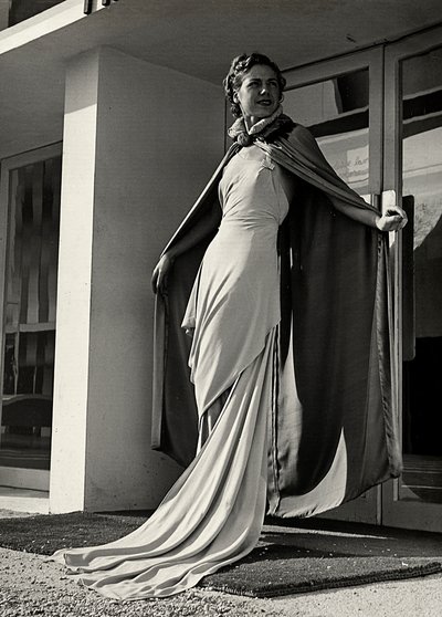 Model i aftenkjole skabt af couture-huset "Graldi". Artiklen er suppleret med en kappe af let stof. (s/h foto) af Luis Bogino