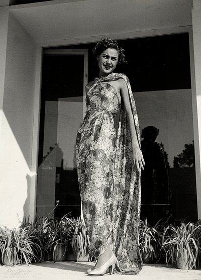 Model bærer en lang kjole med et blomstermønster skabt af couture-huset "Graldi". Artiklen er suppleret med en kappe af samme stof. (s/h foto) af Luis Bogino