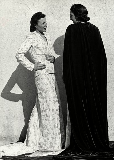 To modeller præsenterer kreationer af det italienske couture-hus "Dragoni". Den ene model bærer et outfit i blemateriale bestående af en jakke og lang nederdel med tog. Den anden model, set bagfra, bærer en lang fløjlskappe. (s/h foto) af Luis Bogino