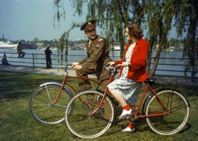 En officer fra den amerikanske hær sidder på cykler nær en havn og flirter med en ung kvinde på Trini... af Luis Marden