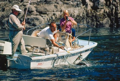 En lystfisker filmer sin fangst, mens han hiver en laks ind ved Bute Inlet. af Ted Spiegel
