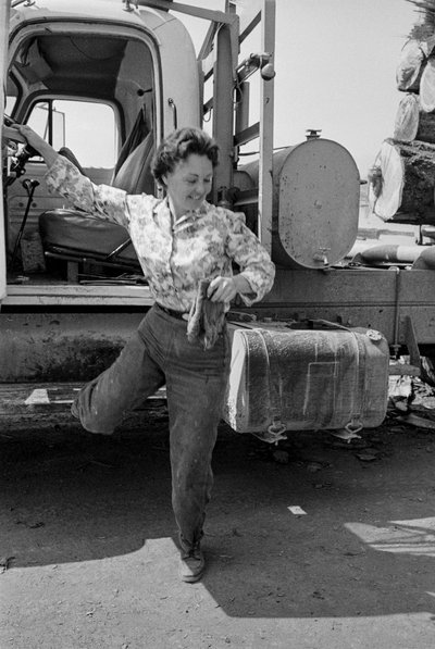 Den kvindelige lastbilchauffør Mildred Cooper træder ud af førerhuset på sin tømmerbil. af Ted Spiegel