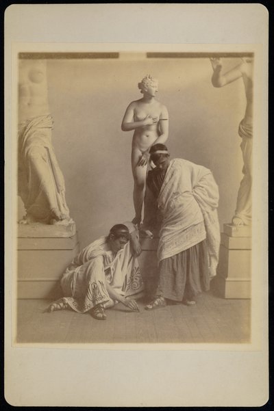 [To mandlige studerende i græsk kostume foran en gipsafstøbning af Afrodite i afstøbningsrummet på Pennsylvania Academy]. af Thomas Eakins