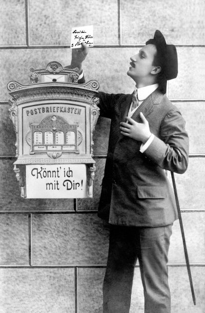 En elegant mand i jakkesæt, hat og stok, lægger en seddel i en postkasse. Tyskland omkring 1920 Historisk fotografi, mand ved siden af en postkasse, omkring 1920 af Unbekannt