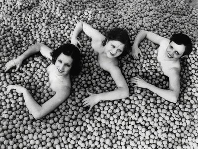 Tre unge kvinder bader i et hav af valnødder. Amerika. 1932 af Unbekannt