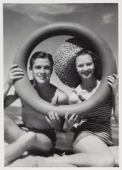 Mand og kvinde kigger gennem en gummiring på stranden, c 1935 af Unbekannt