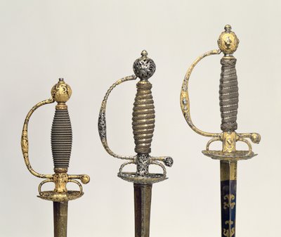 Hilt af tre franske sværd: et af stål, blåt og overtrukket med mønstre i jaget guld, ca. 1730; en af stål gennemboret og mejslet og slebet af matteret guld, c.1760; en af mejslet stål, gr af Unbekannt Unbekannt
