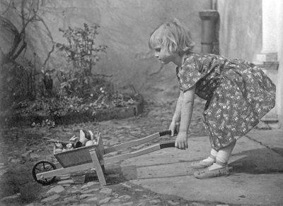 Lille pige leger med en trillebør. Fotografering omkring 1931 af Unbekannt