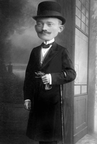 Portræt af en meget elegant mand med et kæmpehoved, han bærer en melonhat, en stok, en butterfly og en sort frakke. Dette er en fotomontage. Annees 1910 Historisk fotografi, mand med kæmpehoved af Unbekannter Künstler