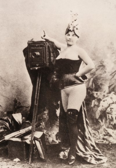 Portræt af en delvist nøgen kvinde, der læner sig op ad et antikt kamera. af Unknown photographer