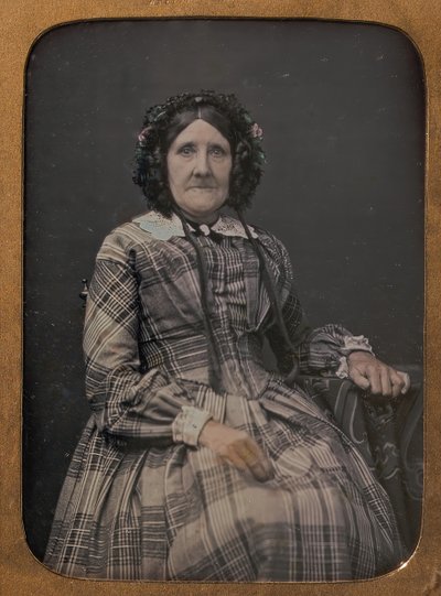 Siddende ældre kvinde iført plaid kjole og hætte, 1854-60. af William Hardy Kent
