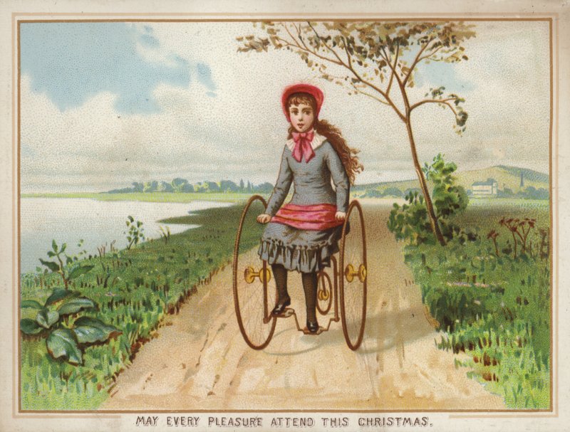 Pige kører på en trehjulet cykel på landet af American School