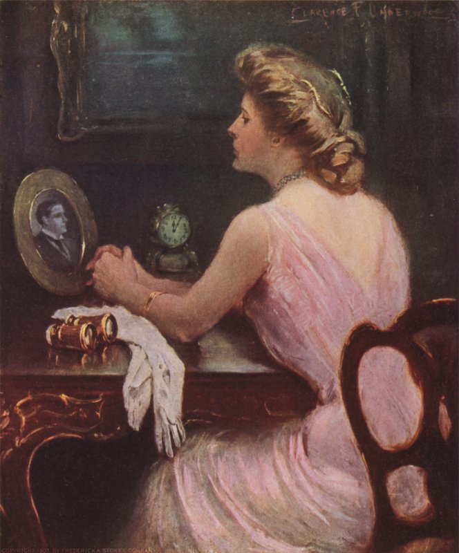 Kvinde sidder ved sit toiletbord og ser på et fotografi af en mand, muligvis hendes mand eller elsker af Clarence F. Underwood
