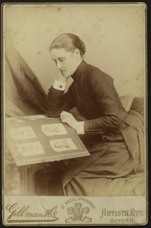 Figur af en kvinde, der sidder og inspicerer et fotoalbum af English Photographer