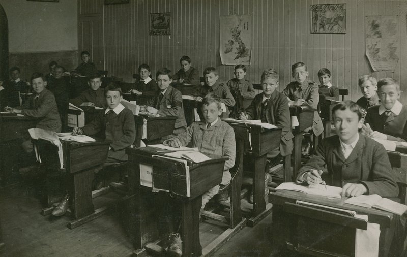 Mandlige elever, der sidder bag deres skriveborde under en lektion i skolen af English Photographer