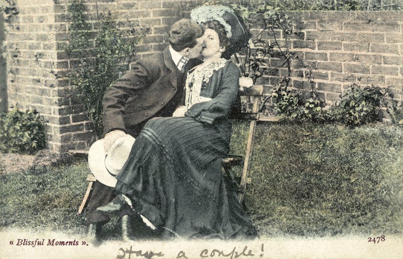 Mand snupper et kys fra en pige på en havebænk (farvefoto) af English Photographer