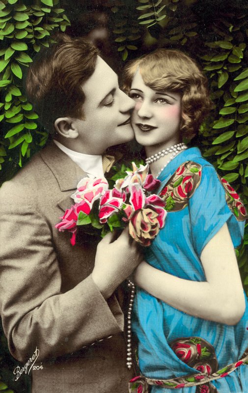 Mand, der bærer blomster, kysser smuk pige på kinden af French Photographer
