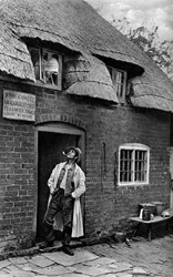 En mand, der ryger pibe uden for en butik, Worcestershire, c1922.