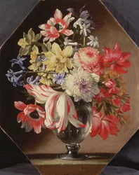 En glasvase med blomster på en stenkant med tulipaner, krysantemum, roser og blåklokker
