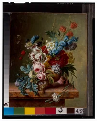 En vase med blomster på en marmorafsats & en kurv med blomster med en guldfink