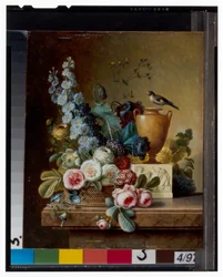En vase med blomster på en marmorafsats & en kurv med blomster med en guldfink