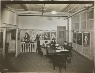 Hovedkontor/receptionslokale på Mutual Film Co. med sekretær ved skrivebordet, folk ved et bord, der læser, og portrætter på væggen, New York