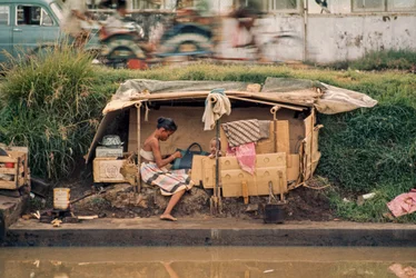 En paphytte langs en spildevandskanal fungerer som hjem. Jakarta, Indonesien.