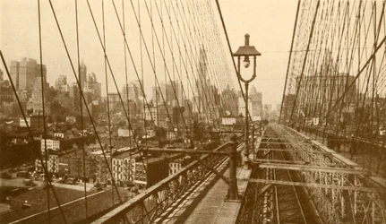 Lower Manhattan set gennem netværket af kabler på Brooklyn Suspension Bridge, c1930.