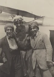 [Portræt af tre mænd, der smiler foran en flyvemaskine].