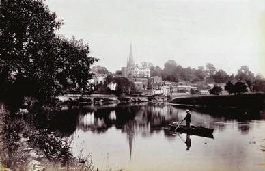 Byen Ross-On-Wye, set fra en flodbred. I forgrunden en mand, der står på en robåd