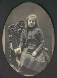[Pige med ringe, siddende, trekvart længde], 1890