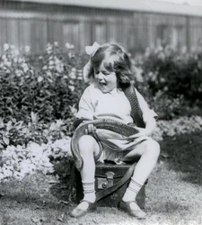 En ung pige Betty holder en østlig indigo slange, mens hun sidder på en læderstamme, London Zoo, 1924