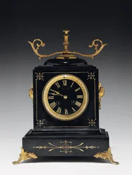 A mantle clock of black composition stone, with incised decoration, with legs, finials and fittings in gilt brass, by Jausions of Pau, France, c.1876-78dani