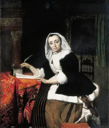 En elegant dame, der skriver ved sit skrivebord, med en hund ved siden af sig
