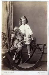 Ung pige sidder på en gyngehest, 1860